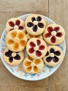 a white plate topped with small cookies covered in jelly and orange slices on top of a wooden table