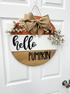 a wooden sign that says hello to pumpkin hanging on a white door with a bow