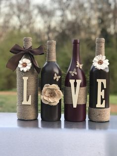 three wine bottles decorated with burlocks and flowers