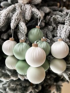 christmas ornaments are hanging from the top of a pine tree in white and green colors