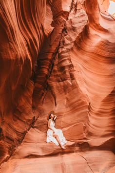 a woman sitting in the middle of a canyon