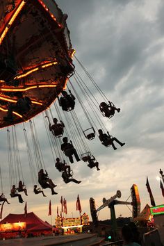 several people are riding on swings at an amusement park