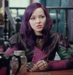 a woman with purple hair sitting at a table