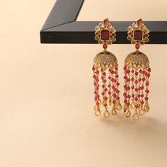 Description: These jhumki earrings from Tarinika are a classic piece with a statement yet simple style. It showcases polki stones set on a floral arrangement having a jhumki drop with beads chain on a gold-plated base. The beaded chains and the minimal design add to its sophistication and richness. Details & Specifications: Materials used: Brass Alloy with Yellow Gold Plating Weight - Earrings 29.13 gm Length - Earrings 9 cm Make it custom Want to make it a custom earring? Sure! Reach out to us Festive Dangle Jhumkas With Tilla, Traditional Dangling Beads Earrings For Reception, Dangle Jhumkas For Diwali Festivities, Festive Dangle Jhumkas For Diwali, Festive Fusion Chandelier Earrings With Latkans, Festive Fusion Style Dangle Danglers, Festive Fusion Dangle Danglers, Festive Latkans Jhumkas Dangle Earrings, Fusion Style Festive Jhumkas With Stone Work