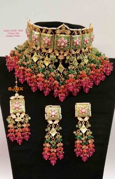 an elaborate necklace and earring set with pink, green and red beads on display