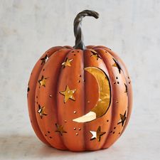 a carved pumpkin with black stars and moon on it's face, sitting on a white surface