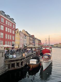 several boats are docked in the water next to some buildings with bicycles parked on them