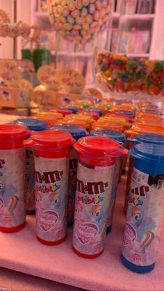 there are many cups on the table with candy in front of them and some candies behind it