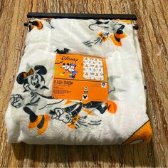 the mickey mouse blanket has been folded up on top of a wooden table with an orange tag