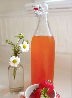 a pitcher of liquid next to a bowl of strawberries