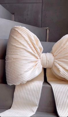 a large white bow tie sitting on top of a metal stair case next to a wall