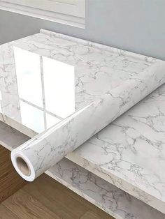 a roll of white marble paper sitting on top of a wooden floor next to a window