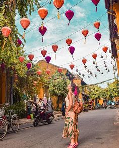 a woman walking down the street with lots of lanterns hanging from it's ceiling