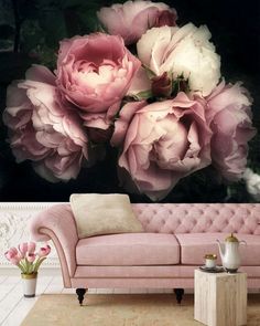 a pink couch sitting in front of a wall with large flowers on it's back