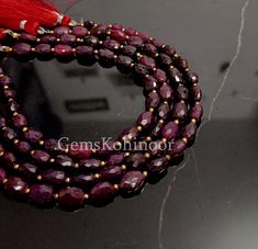 two strands of red glass beads on a black surface