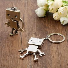 a metal robot keychain sitting on top of a wooden table next to flowers