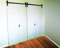 an empty room with white doors and wood flooring