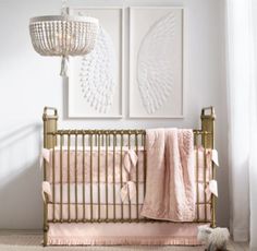 a baby crib with pink and white decor in the corner next to two pictures on the wall