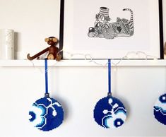 three ornaments are hanging on a shelf in front of a framed picture and a monkey