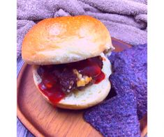 a close up of a sandwich on a plate with some purple chips next to it