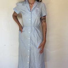 50s/60s light blue workers midi length utility dress uniform with big side pocket  minor staining throughout  pit to pit 21in shoulders: 18in sleeve: 7in waist: 14.5in hip: 21in length: 49in Washed Blue Short Sleeve Dress With Pockets, Blue Cotton Midi Dress With Pockets, Collared Midi Dress With Pockets For Daywear, Light Blue Button-up Dress With Pockets, Light Wash Collared Dress With Pockets, Vintage Midi Dress With Pockets, Cotton Midi Dress With Pockets For Work, Vintage Blue Dresses With Pockets, Blue Vintage Dresses With Pockets