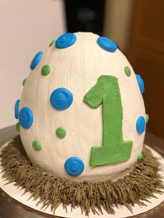 a white cake with blue and green frosting on it's top that says 1