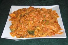 a white plate topped with pasta and broccoli on top of a green table