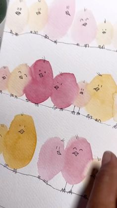 someone is drawing on some paper with watercolors