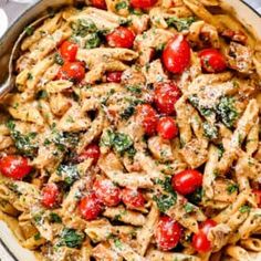 pasta with tomatoes, spinach and parmesan cheese in a skillet on a table