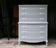 an old dresser is painted gray with white trim