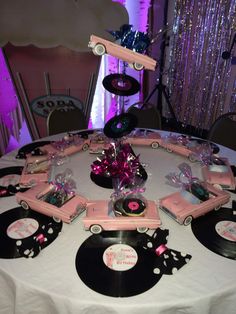 a round table topped with black and pink record records covered in plastic wrap, surrounded by disco balls