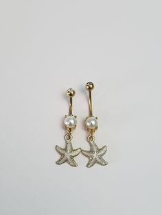 Embrace your unique beauty with our Gold and White Starfish Belly Button Ring, crafted from premium 316L gold anodized stainless steel to offer both elegance and durability. Specifically designed for plus size individuals, it comes in 2 custom sizes (12mm and 14mm) to ensure the perfect fit and utmost comfort. Our collection at Big Belly Bling is committed to providing high-quality, stylish jewelry that celebrates every body type. Let your personality shine with this captivating piece that's both chic and versatile. Discover the perfect blend of style and function tailored just for you! 5mm steel top ball with clear acrylic gem.  Gem is embedded past rim of steel ball to protect against scratches and falling off. Beige starfish - 15mm x 18mm with 7mm acrylic pearl Dangly Belly Ring, Unique Belly Rings, Cute Belly Rings, Bellybutton Piercings, Belly Button Piercing Jewelry, Belly Piercing Jewelry, Belly Button Jewelry, Belly Jewelry, Body Jewelry Piercing