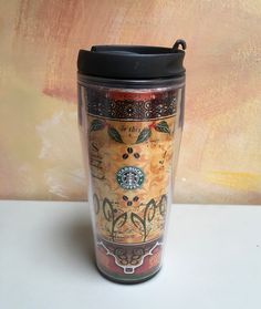 a starbucks cup sitting on top of a white table next to a brown and orange wall