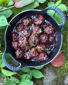 meatballs are cooked in a skillet on the ground with green leaves around them