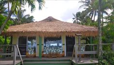 a small hut with thatched roof and steps leading to the deck area in front of it