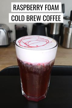 raspberry foam cold brew coffee in a glass on top of a black tray