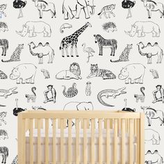 a baby's crib in front of a white wall with black and white animals on it