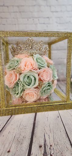 a bridal bouquet in a gold frame on a wooden table with white brick wall behind it