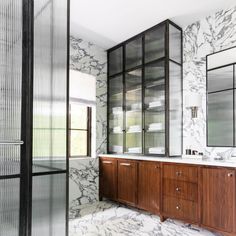 a bathroom with marble walls and cabinets in the shower area, along with glass doors