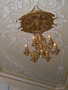 a chandelier hanging from the ceiling in a room with white and gold wallpaper