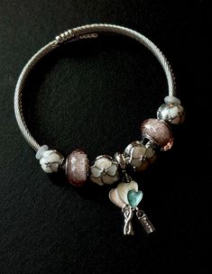 a bracelet with charms on it sitting on top of a black surface and the clasp is open