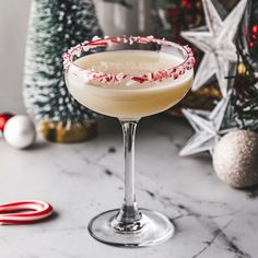 a drink in a glass with candy canes on the rim next to christmas decorations