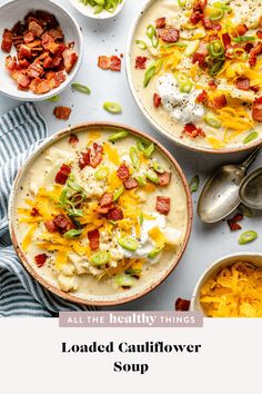 loaded cauliflower soup in two bowls with spoons and bacon on the side