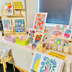 many cards are displayed on a table in front of a chalkboard with fruit and flowers