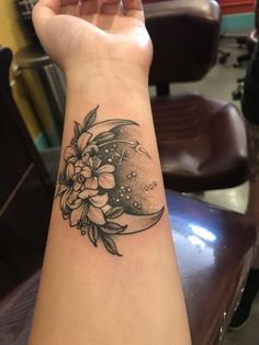 a woman's arm with a flower and moon tattoo on the left side of her arm