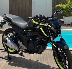 a black and yellow motorcycle parked next to a swimming pool