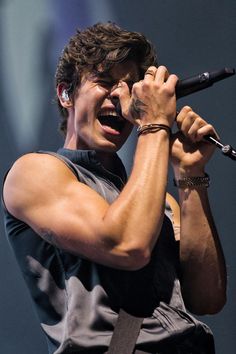 a man holding a microphone in his right hand and singing into the microphone on stage