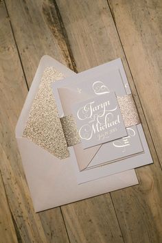 two wedding cards on top of each other with gold glitter and white paper in the middle