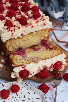 a cake with white frosting and raspberry toppings on a wooden board