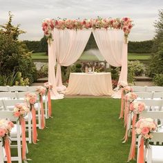 an outdoor wedding ceremony setup with white chairs and pink sashes on the grass, decorated with flowers